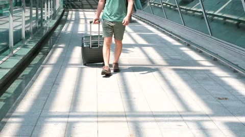 Young man rolls green suitcase near the airport, travel concept. Stock Footage 248698170