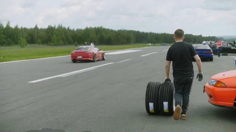 Young man rolls two new, freshly assembled wheels along the road rear view Stock Footage 129345820