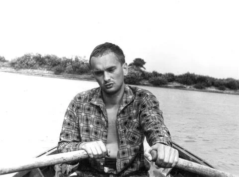 Young man rowing boat on river in plaid shirt 1960s Photos