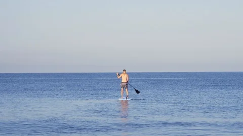 A young man rowing an pddle standing on the Board. Sup board on the sea. Vidéo 114273968