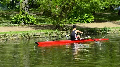 Young man rowing a red boat Stock Footage 11090578