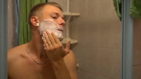 The young man rubs his face with shaving cream Stock Footage 79192789