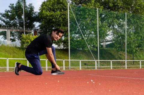 Young man runner doing stretching exercise, preparing for morning workout Stock Photos