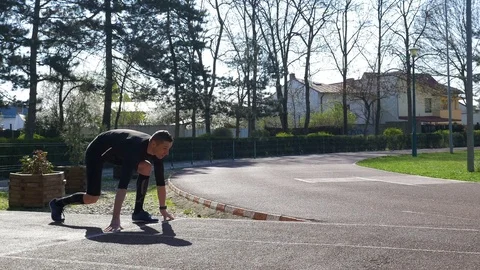 Young man runner at starting line in block start position on race track train Stock Footage 77737789