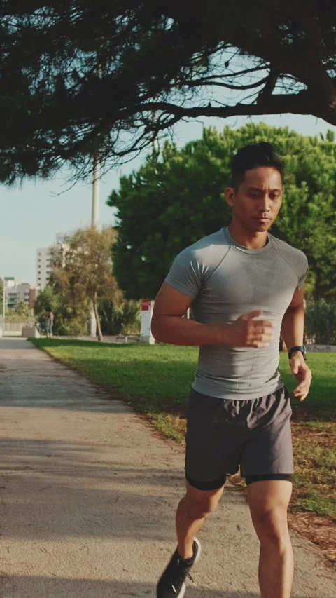 Young man running along the path in the park Stock Footage 252031498