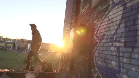 Young Man Running Along Rooftop at Sunset Stock Footage 82353406