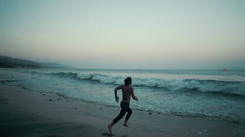 Young Man Running And Jumping Into Ocean. 120fps Stock Footage 64654928