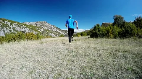 Young man running away on mountain trail in the alpine meadow Stock Footage 48900696