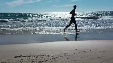 Young man running on the beach Stock Footage 212283962