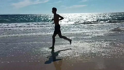 Young man running on the beach Stock Footage 212283973