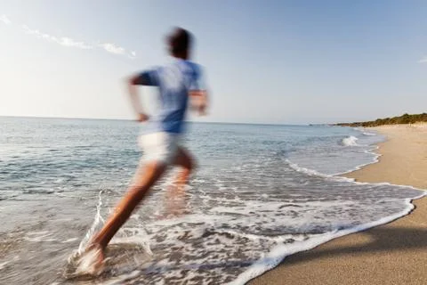 Young man running on a beach. Stock Photos