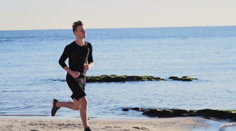 Young man running on the beach slow motion Stock Footage 57296005