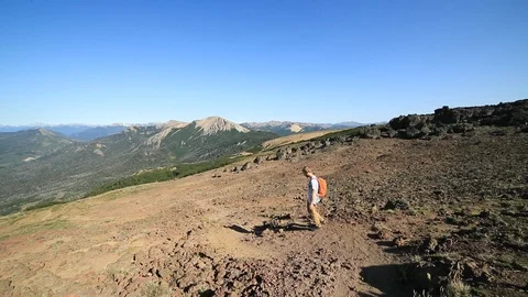 Young man running down a volcano. Background of woods and andes mountain chain 스톡 동영상 126729364