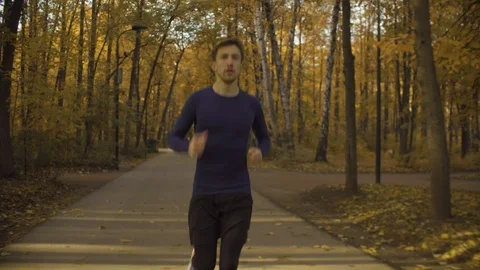 Young man running fast along the road in the park Stock Footage 102701118