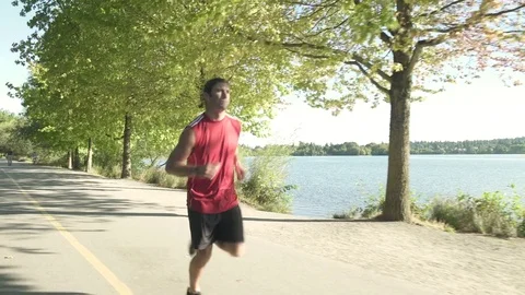 A young man running by a lake 스톡 동영상 76223663