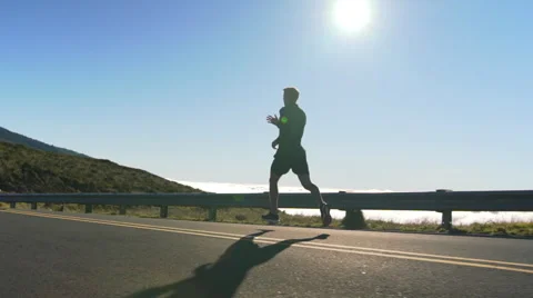 Young Man Running on Mountain Road at Sunset Above the Clouds. Slow Motion HD Stock Footage 59817192