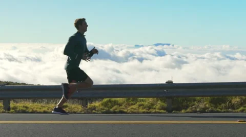 Young Man Running on Mountain Road at Sunset Above the Clouds. Slow Motion HD Stock Footage 59818937