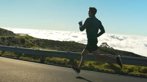 Young Man Running on Mountain Road at Sunset Above the Clouds. Slow Motion HD Stock Footage 59821143