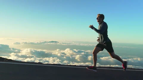 Young Man Running on Mountain Road at Sunset Above the Clouds. Slow Motion HD Stock Footage 59823302