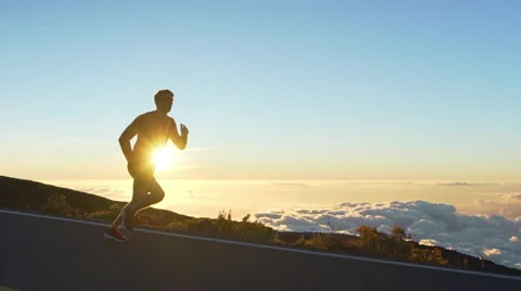 Young Man Running on Mountain Road at Sunset Above the Clouds. Slow Motion HD Stock Footage 59824574