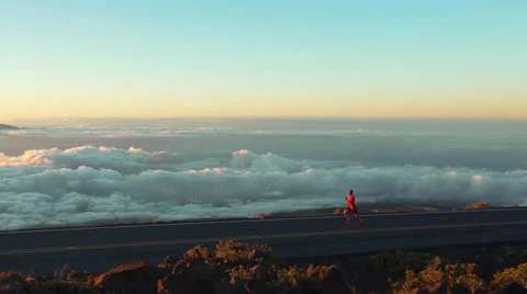 Young Man Running on Mountain Road at Sunset Above the Clouds. Slow Motion HD Stock Footage 59825523