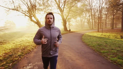 Young man running in park during sunny autumn morning Stock Footage 158914184