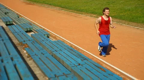 Young man running through the stadium track Stock Footage 1102173