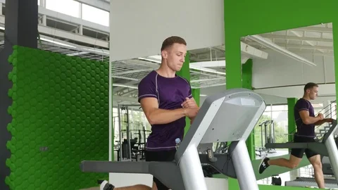 Young man running on treadmill and drinking water Stock Footage 77763440