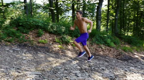 Young man running uphill in forest Stock Footage 55865775