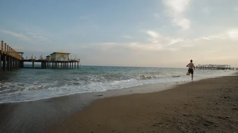 Young man running on the water's edge along the sea, healthy lifestyle, sport Stock Footage 51252831