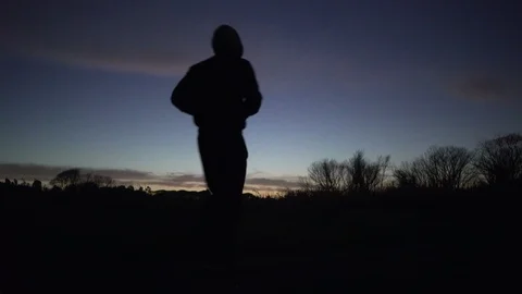 A young man runs in a park during sunset in silhouette Stock Footage 101759873