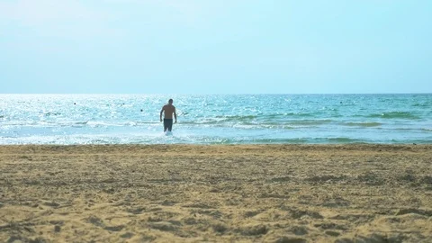 Young man runs on a sandy beach at sea Stock-Footage 116135249