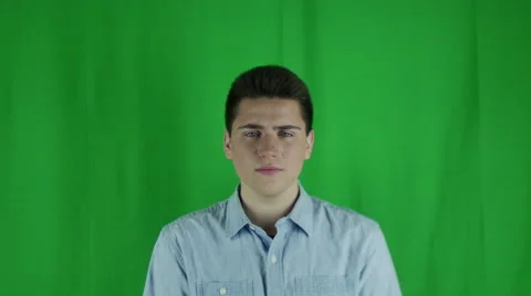 Young man is sad in front of a greenscreen in a blue shirt Vidéo 59082747