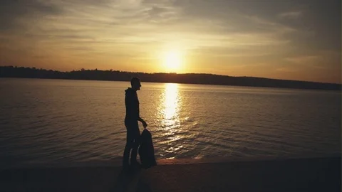 The young man sadly walks on the background of sunset near the river Stock Footage