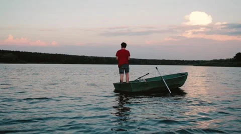 Young man sailing boat on the river and fishing, sunset Stock Footage 66284833