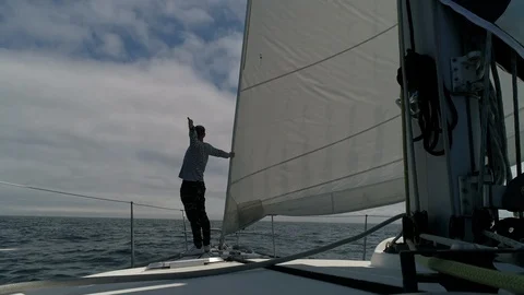 A young man sailor on the deck of a sailing yacht in the ocean looks forward  스톡 동영상 114811727