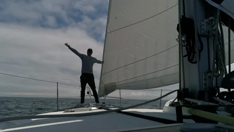 A young man sailor on the deck of a sailing boat in the ocean looks forward. Stock-Footage 114811963