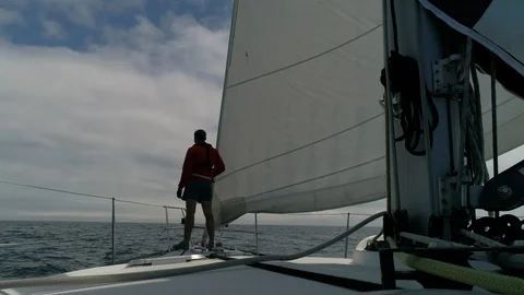 A young man sailor on the deck of a sailing boat in the ocean looks to horizon 스톡 동영상 114814529