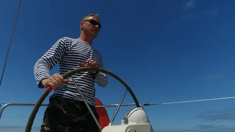 A young man sailor at the helm of a sailing yacht turns the steering wheel. Vidéo 114818542