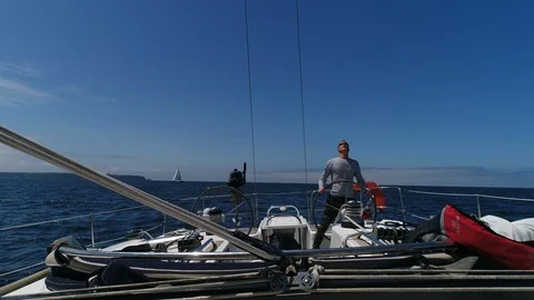 A young man sailor at the helm of a sailing yacht turns the steering wheel. Stock Footage 115993316