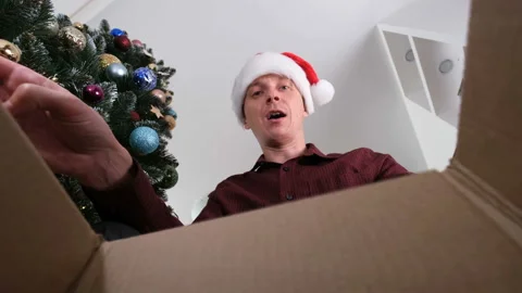 Young Man in Santa Hat Open the Gift Box and Takes Gift out of the Box Stock Footage 144804007