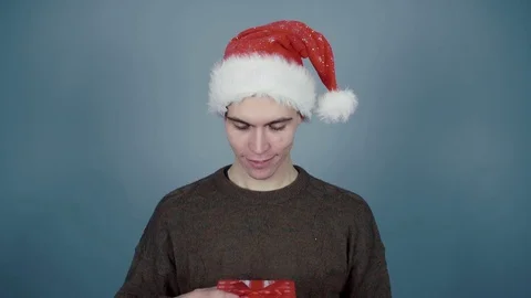 Young man in Santa hat opening a gift box and seeing calling smartphone inside Stock Footage 70223372