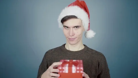 Young man in Santa hat opening a gift box with a surprise inside seeing Fuck You Stock Footage 70223893