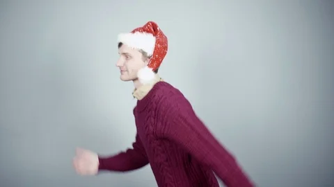Young man in santa hat running and smiling at studio gray background Stock Footage 70261010