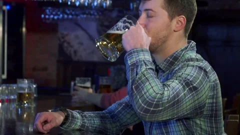 Young man savoring a refreshing beer at a lively pub Stock Footage 311935726
