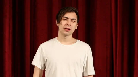 Young man saying no by shaking head against red curtain background Stock Footage 112216419