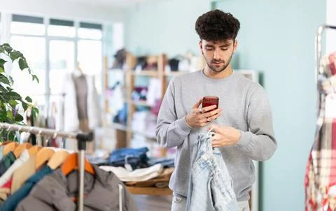 Young man scanning qr code of jeans in store Foto stock
