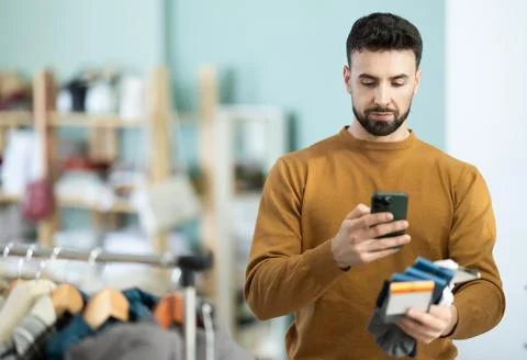 Young man scanning QR-code on socks in clothing store Stock-Fotos