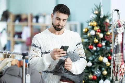 Young man scanning qr code of sweater in store Foto stock