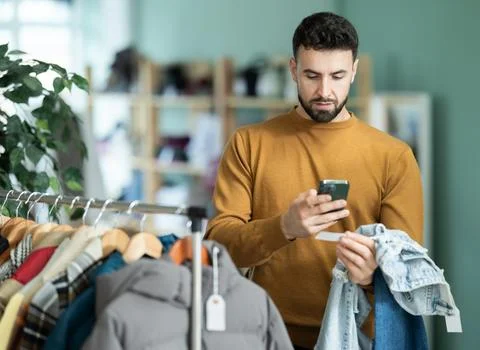 Young man scanning qr code of jeans in store Foto stock